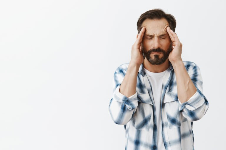 Pissed off man trying control anger, massaging temples with closed eyes, trying calm down, feeling headache or suffering from migraine, having bad day and asking for painkillers over gray background. Copy space